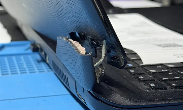 Notebook com dobradiça e carcaça quebradas na bancada da VITECH, em Mossoró